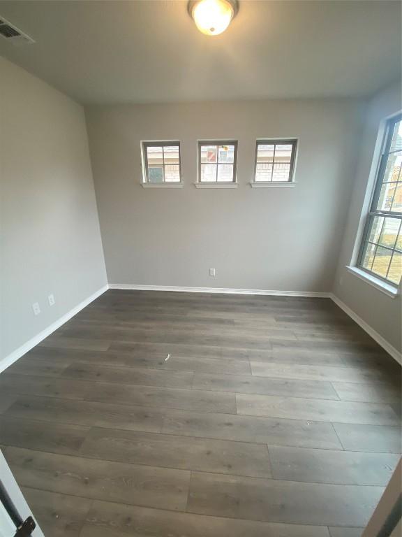 spare room featuring visible vents, baseboards, and dark wood finished floors