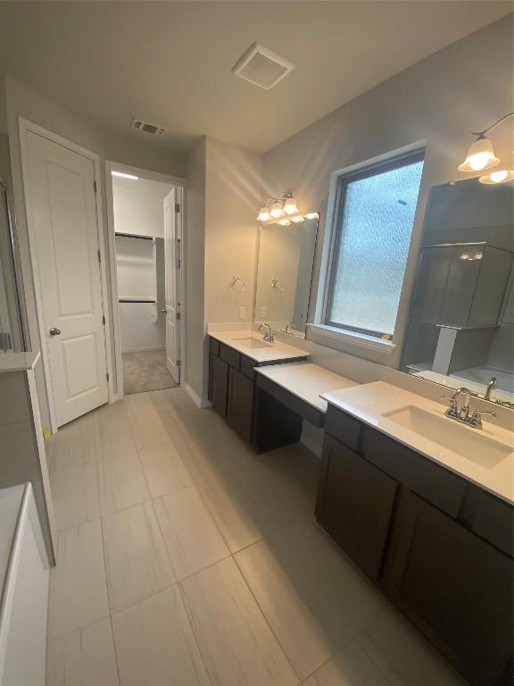 full bathroom with visible vents, two vanities, a sink, and a shower stall