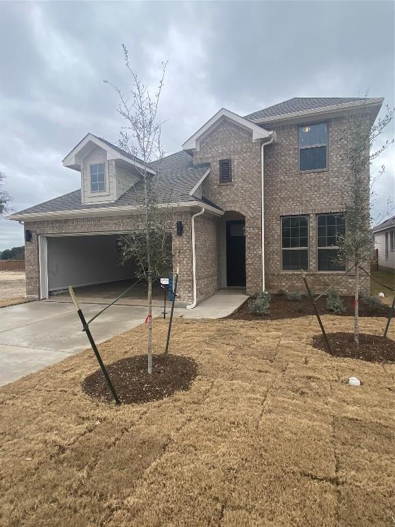 traditional home featuring driveway, an attached garage, and brick siding