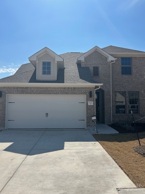 view of front of property featuring a garage, driveway, and brick siding