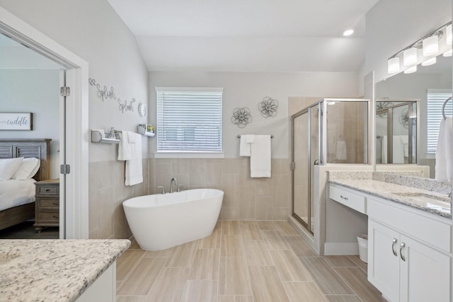 bathroom featuring tile patterned floors, tile walls, vanity, and separate shower and tub