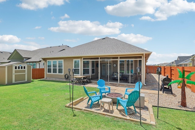 back of house with a lawn, a patio, an outdoor fire pit, and a storage unit