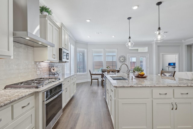 kitchen with appliances with stainless steel finishes, sink, ornamental molding, and wall chimney range hood