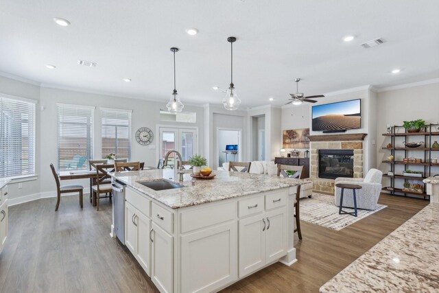 kitchen featuring wood-type flooring, ceiling fan, sink, white cabinetry, and a tiled fireplace