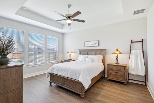 bedroom featuring hardwood / wood-style floors, a tray ceiling, and ceiling fan