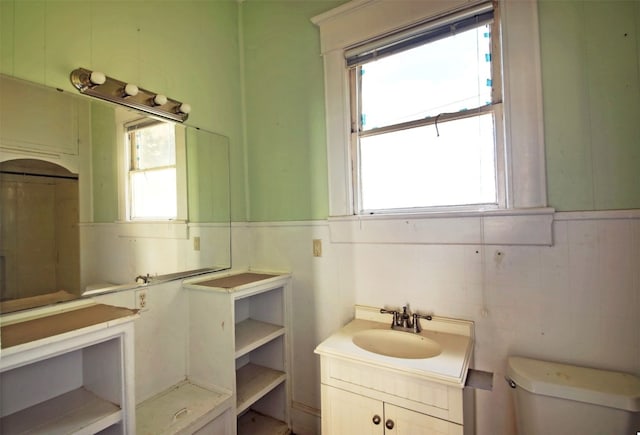 half bathroom with toilet, plenty of natural light, and wainscoting