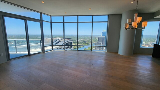 spare room featuring a notable chandelier, a wall of windows, and hardwood / wood-style flooring