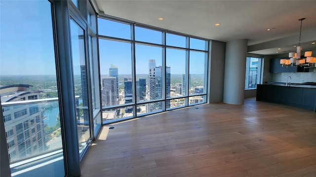 unfurnished living room with a notable chandelier, hardwood / wood-style floors, and a wealth of natural light