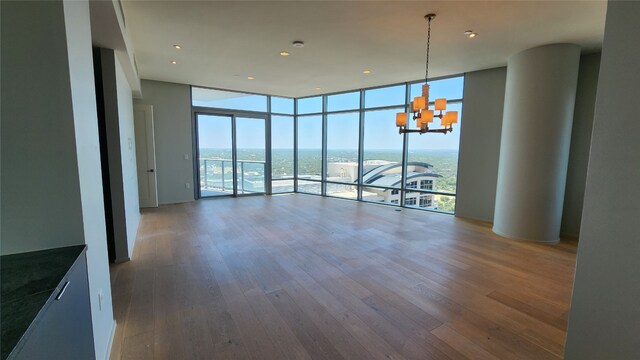 unfurnished room featuring floor to ceiling windows, wood-type flooring, and a healthy amount of sunlight