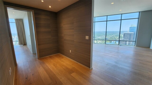 empty room featuring a wall of windows and light hardwood / wood-style floors