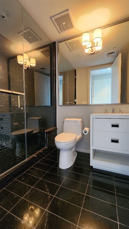 bathroom with a shower with door, toilet, tile patterned floors, vanity, and an inviting chandelier