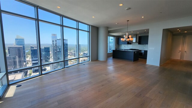 unfurnished living room with sink, floor to ceiling windows, hardwood / wood-style floors, and an inviting chandelier