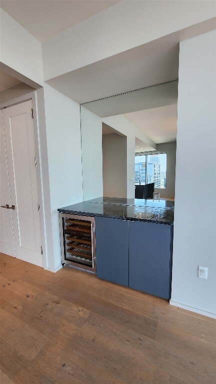 kitchen featuring wine cooler, dark stone countertops, and hardwood / wood-style flooring