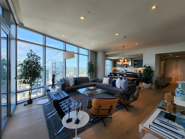 living area with a chandelier, recessed lighting, expansive windows, wood finished floors, and a view of city