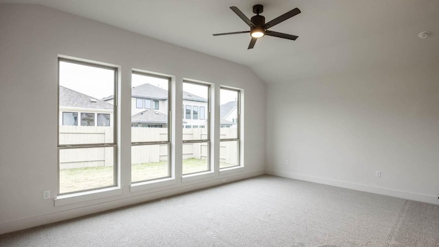 carpeted spare room featuring vaulted ceiling, ceiling fan, and baseboards