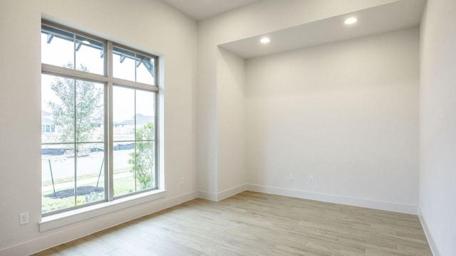 empty room with light wood finished floors, recessed lighting, and baseboards