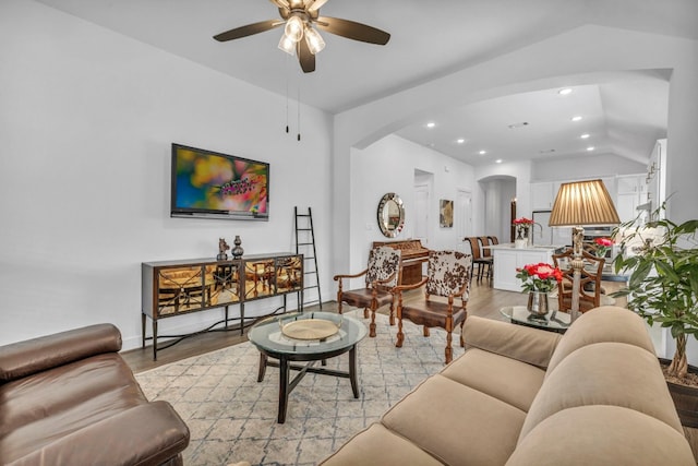 living room featuring ceiling fan, vaulted ceiling, and light hardwood / wood-style flooring