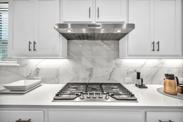 kitchen with wall chimney exhaust hood, tasteful backsplash, white cabinets, and stainless steel gas stovetop