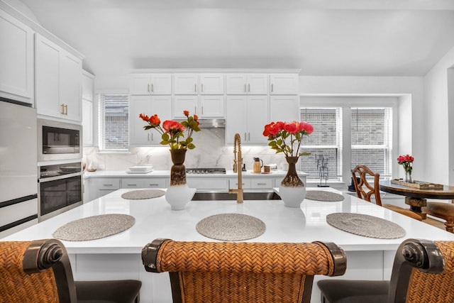 kitchen featuring white cabinetry, appliances with stainless steel finishes, tasteful backsplash, and a breakfast bar