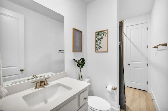 bathroom featuring toilet, vanity, and wood-type flooring