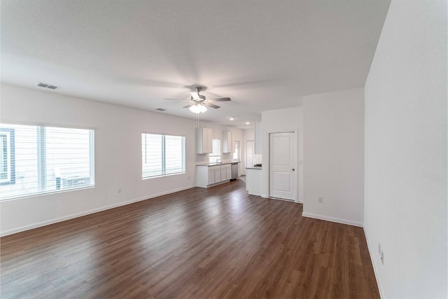 unfurnished living room with ceiling fan, dark wood-style flooring, visible vents, and baseboards