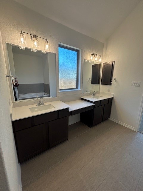 full bathroom with vaulted ceiling, vanity, a bath, baseboards, and tile patterned floors