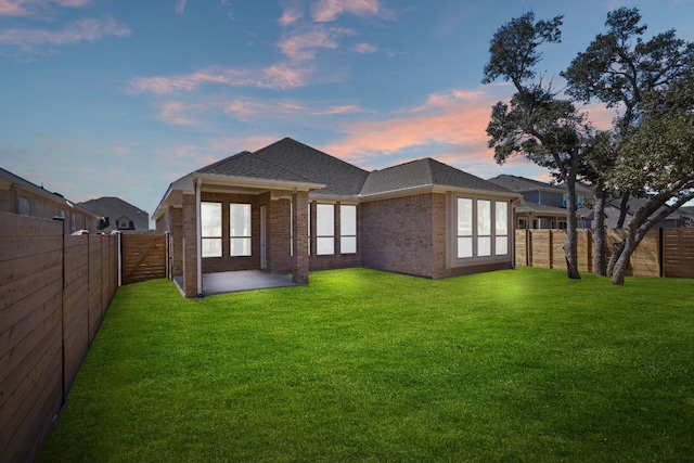 520 Raleigh Dr, Georgetown, TX 78633 - back of property at dusk featuring brick siding, a fenced backyard, roof with shingles, and a patio area