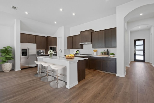 520 Raleigh Dr, Georgetown, TX 78633 - kitchen featuring appliances with stainless steel finishes, arched walkways, light countertops, a center island with sink, and tasteful backsplash