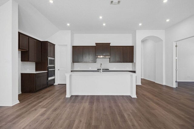 520 Raleigh Dr, Georgetown, TX 78633 - kitchen featuring stainless steel appliances, arched walkways, tasteful backsplash, light countertops, and a kitchen island with sink