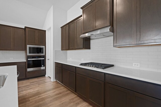 520 Raleigh Dr, Georgetown, TX 78633 - kitchen featuring appliances with stainless steel finishes, under cabinet range hood, light countertops, dark brown cabinets, and tasteful backsplash