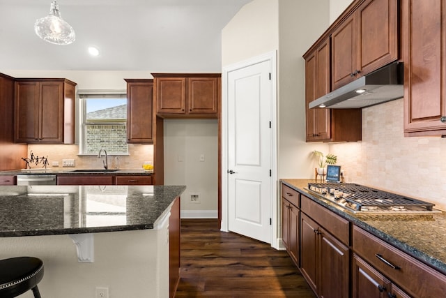 kitchen with pendant lighting, dark hardwood / wood-style flooring, dark stone countertops, and stainless steel appliances