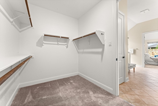 walk in closet with light colored carpet and lofted ceiling