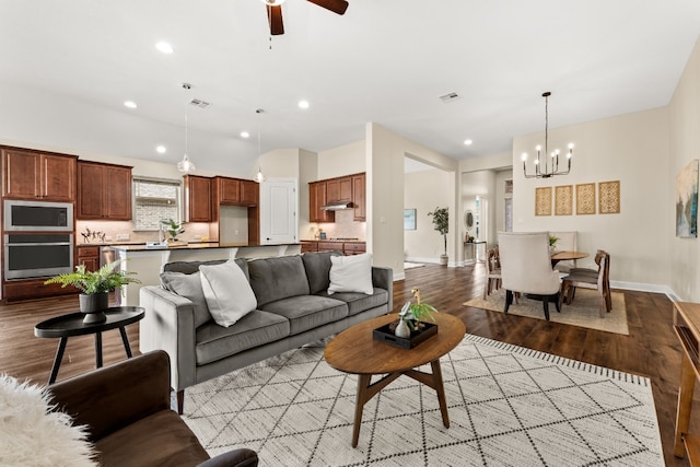 living room featuring ceiling fan with notable chandelier and light wood-type flooring