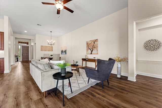 living room featuring dark wood-type flooring and ceiling fan with notable chandelier