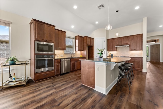 kitchen featuring dark hardwood / wood-style flooring, a center island with sink, stainless steel appliances, and lofted ceiling