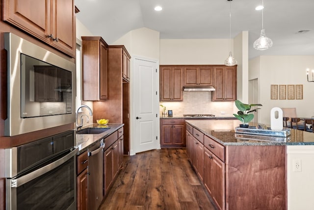 kitchen featuring a center island, sink, dark stone countertops, dark hardwood / wood-style flooring, and stainless steel appliances