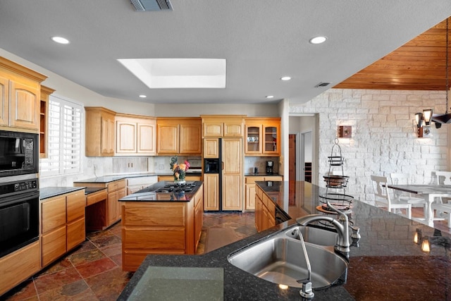 kitchen with a center island, black appliances, sink, a skylight, and tasteful backsplash