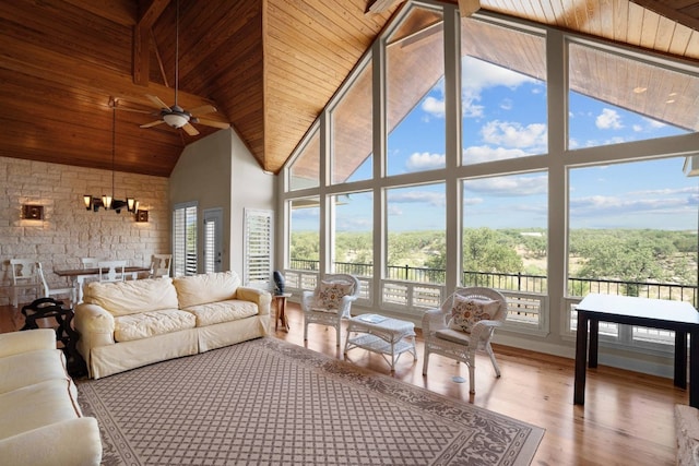 sunroom / solarium with ceiling fan with notable chandelier, wood ceiling, and vaulted ceiling