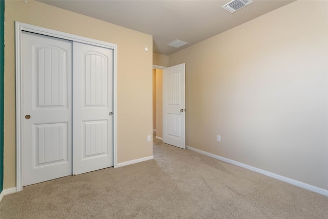 unfurnished bedroom with light carpet and a closet