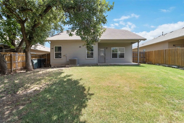 rear view of house featuring central AC and a yard