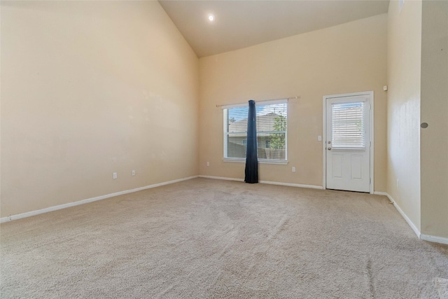 spare room featuring high vaulted ceiling and light colored carpet