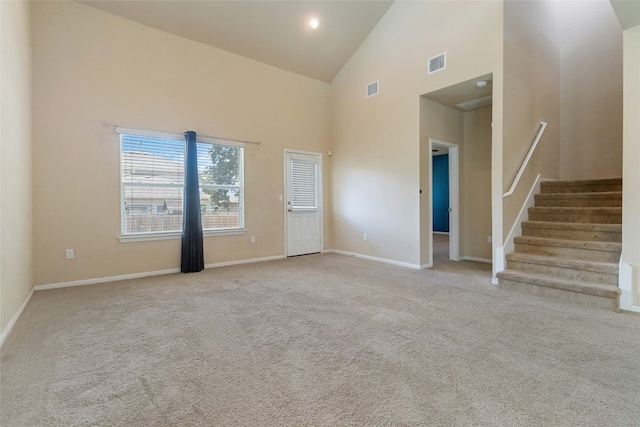 carpeted empty room with high vaulted ceiling