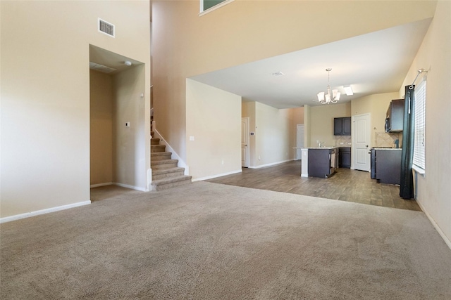 unfurnished living room with an inviting chandelier and carpet floors