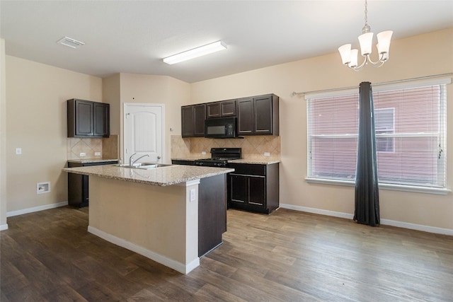 kitchen with backsplash, stove, wood-type flooring, and a kitchen island with sink