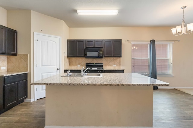 kitchen with light stone counters, range, hardwood / wood-style flooring, and pendant lighting