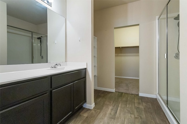 bathroom with wood-type flooring, vanity, and a shower with door