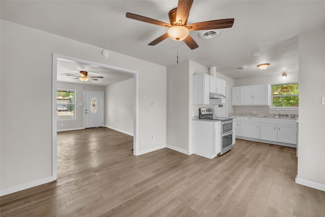 kitchen featuring light hardwood / wood-style flooring, white cabinets, a healthy amount of sunlight, and range with two ovens