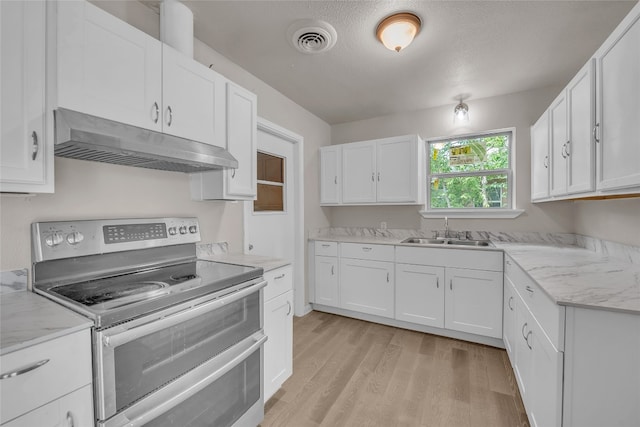 kitchen with light wood-type flooring, double oven range, white cabinetry, light stone counters, and sink