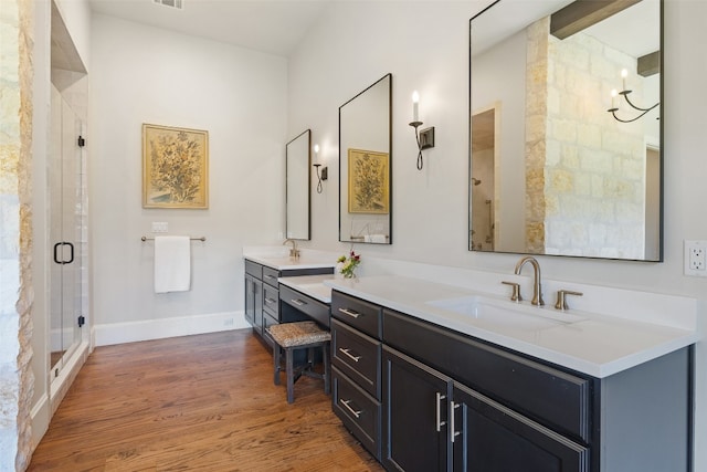 bathroom with hardwood / wood-style floors, a shower with door, and vanity