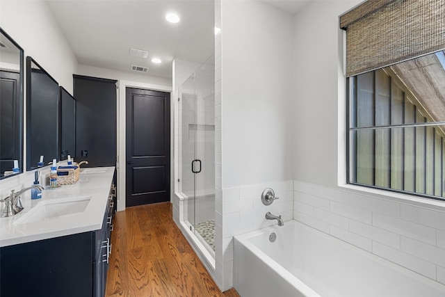 bathroom with hardwood / wood-style flooring, double vanity, and independent shower and bath